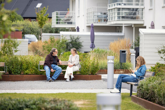 Residents spending leisure time sitting on bench in garden