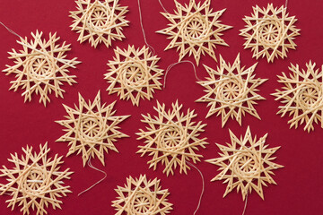 Snowflakes are made of straw on a red background. Christmas decor. Top view. Straw weaving. Lutsk, Ukraine
