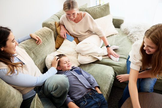 High angle view of boy lying down on sofa while spending leisure time with family at home