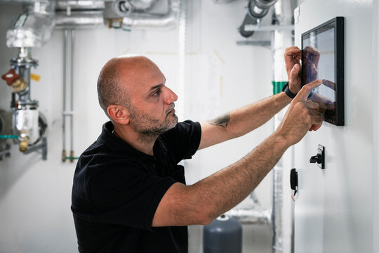 Maintenance engineer using digital tablet mounted on wall in factory