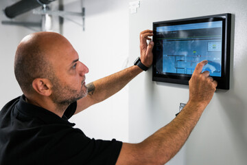 Man examining control panel on digital tablet while working in factory