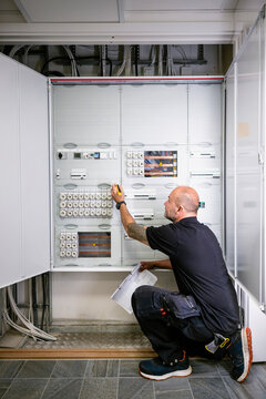 Electrician examining power supply while working in factory