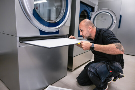 Technician changing filter of washing machine