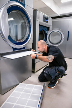 Full length of electrician changing filter of washing machine