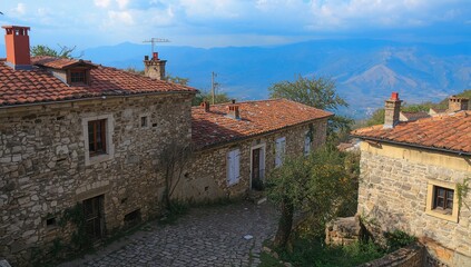 Obraz premium Picturesque vintage stone cottages featuring classic red roofs and chimneys, showcasing rustic mountain village charm.