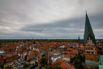 Fototapeta premium Panoramic view of historic city with red rooftops and tall church spire 