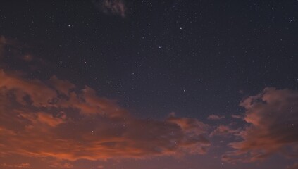 Fototapeta premium An authentic orange dusk featuring stars, clouds, and a deep navy sky