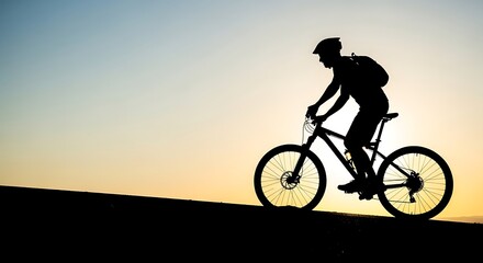Obraz premium Silhouette of a cyclist riding uphill against a vibrant sunset.