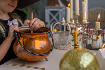 little girl in costumes stir potion in cauldron during fun Halloween play at home, casting spells, mixing potion in cauldron, young witch Halloween party atmosphere, time play witches