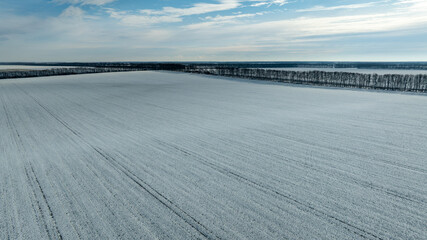 Aerial view of snow-covered agricultural fields. Serene, cold, and beautiful rural scenery.