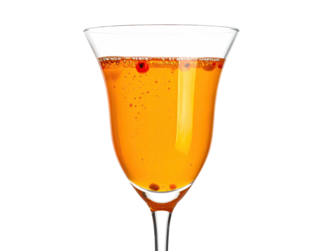 Close-up of a tulip-shaped glass filled with an orange beverage, garnished with small red spheres
