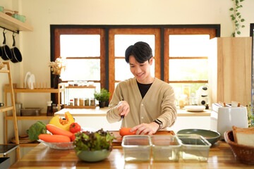 A man is cutting a carrot on a wooden cutting board.