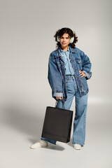 Fashionable young woman with a shopping bag enjoying her stylish outfit in a studio setting