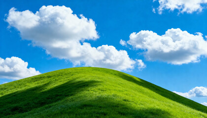 Fototapeta premium Lush green hill under sunny blue sky with scattered white clouds casting shadows on vibrant grassy landscape in spring
