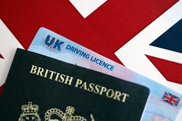 United Kingdom driving license with passport on UK flag close up
