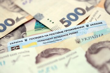 Ukrainian residence permit card or permanent resident card on Ukrainian money close up