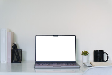 Minimal workspace with laptop on white desk, blank screen ready for design or presentation.