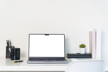 Fototapeta premium Laptop, book and coffee cup on white desk, blank screen ready for design or presentation.