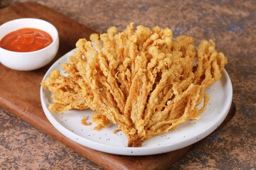 Golden brown crispy fried mushrooms on ceramic plate. Popular street food and appetizer, perfect for restaurant menus or snack ads.