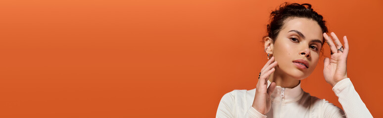 Young woman showcases modern fashion against vibrant orange backdrop