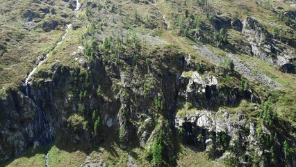 Waterfall cascading down mountainside covered in vegetation. Media