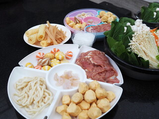 A circular tray divided into sections for thinly sliced ​​marinated pork,  tofu skin, udon noodles, various kinds of meatballs, organic vegetable ser. Fresh food set for menu hot pot, MooKata,Sukiyaki