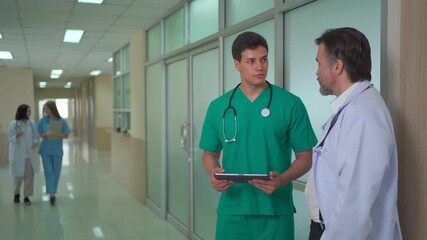 Multinational medical team discussing data on digital tablet in hospital. - Powered by Adobe