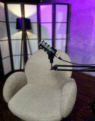 Podcast setup with microphone and cozy chair in purple-lit studio environment