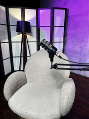 Podcast setup with microphones and a cozy chair in a modern studio space