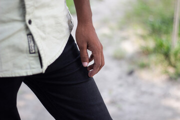 Closeup of a persons hand and torso wearing a lightcolored shirt and dark pants