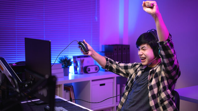 Excited gamer celebrating victory after winning video game at night,