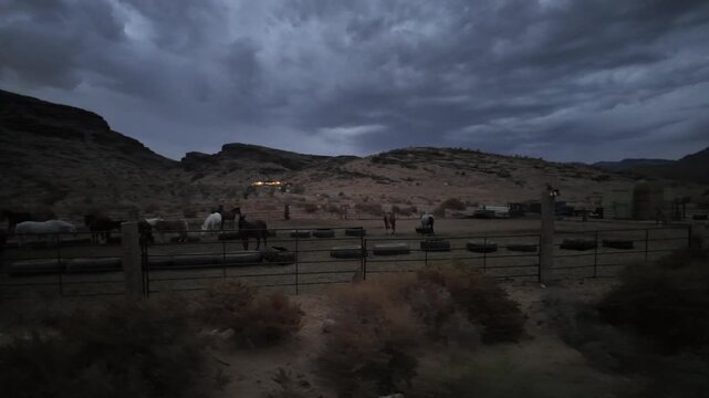 Horseback Riding Near a Stable in a Desert Landscape With Clouds