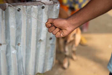 A persons hand is clenched in a fist near a corrugated metal surface
