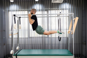 Cadillac and reformer, caucasian man doing Pilates exercises to strengthen body and stretch....