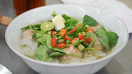 The kwetiau meatball soup at Bakso Bintang Asia Bandung is similar to Pho, a Vietnamese specialty dish served with coriander, basil, cayenne pepper, and lime, served in a white bowl.