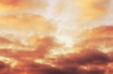 dramatic sky with warm toned clouds illuminated by sunset light evoking tension and sense of impending conflict