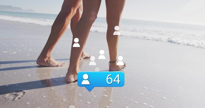 Walking couple's bare legs splashing through wet sandy shoreline, with social notification icons