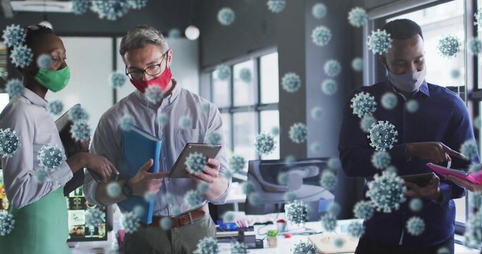 Collaborating coworkers wearing masks around desk at office, with tablets and virus overlays - Powered by Adobe