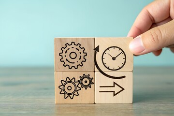 Hand arranging wooden blocks with gears and clock symbols to represent efficiency and time management