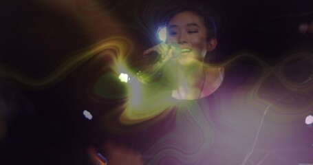 Singing Chinese singer in black long sleeve top on concert stage, with microphone, haze and lights