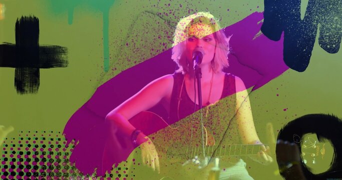 Performing musician strumming guitar and singing with microphone on stage, with abstract splatters