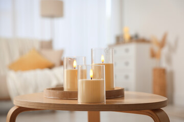 Decorative LED candles on wooden table at home, closeup