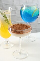 Glasses of tasty cocktails on white table, closeup
