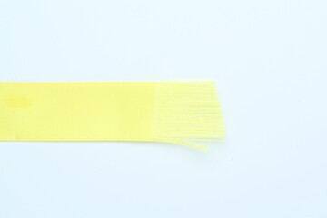 Beautiful yellow ribbon on white background, top view. Space for text