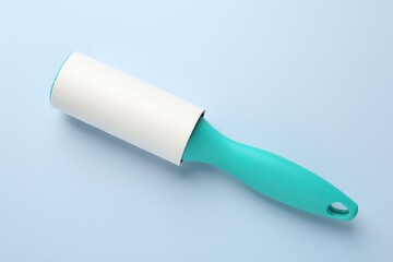 One lint roller on light blue background, top view