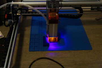 Modern laser engraving machine working with precision under blue industrial lighting in a workshop environment