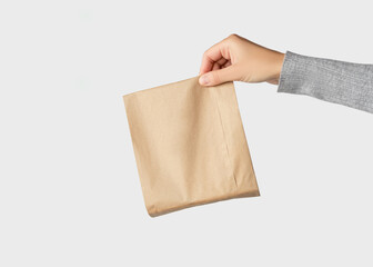Hand holding a small brown paper package on a white background