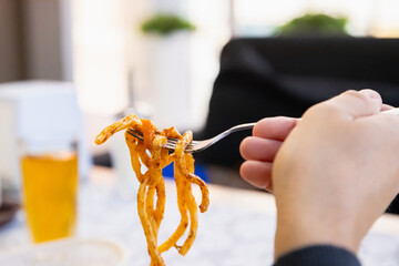 Lagman noodles on fork. man eats bucatini noodles. noodle with meat