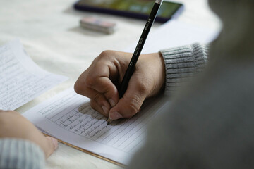 Teenager hand writing studying on notebook with pencil