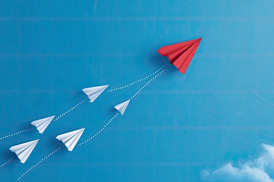 Overhead view showing paper airplanes in flight with a red leader on a blue background